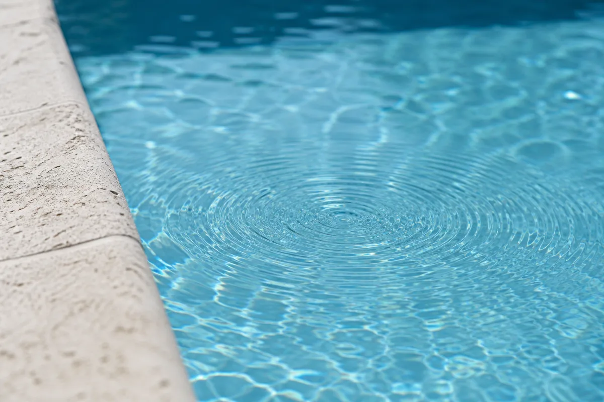 Ondes concentriques à la surface de l&rsquo;eau au ras d&rsquo;une margelle en pierre