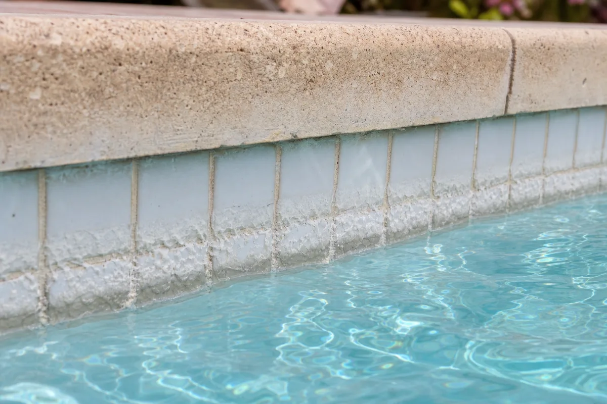 Ligne d&rsquo;eau entartrée sur une paroi de piscine avec dépôts calcaires blancs